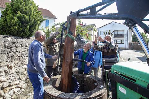 Die Mir Trewwerer beim Aufstellen der renovierten historischen Holzpumpe.