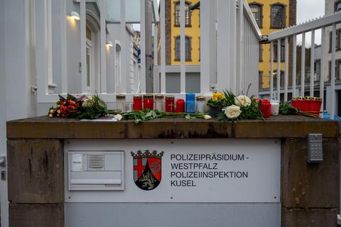 Blumen liegen und Kerzen stehen am Eingang der Polizei in Kusel. Foto: dpa