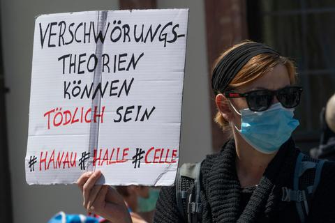 "Verschwörungstheorien können tödlich sein" steht auf dem Schild einer Frau, die sich an einer Demonstration beteiligt, die sich auch gegen Verschwörungstheorien zum Corona-Virus wendet. Foto: Boris Roessler/dpa 