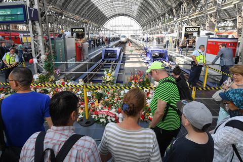 Passanten stehen im Sommer 2019 am Gleis 7 des Frankfurter Hauptbahnhofs vor einem Meer aus Blumen, Kuscheltieren und Beileidsbekundungen. Ein achtjähriger Junge wurde dort am 29. Juli von einem Mann vor einen einfahrenden ICE gestoßen und getötet.  Archivbild: dpa