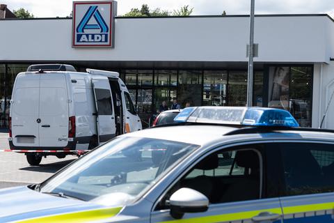 Einsatzfahrzeuge der Polizei stehen vor dem abgesperrten Einkaufsmarkt in Schwalmstadt, in dem ein Mann erst eine Frau und dann sich selbst tötete. Foto: dpa/Swen Pförtner