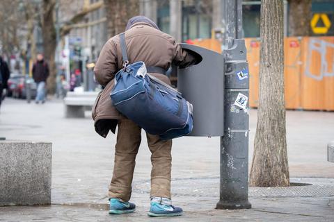 Ein Pfandsammler an einem Mülleimer, mitten in der Stadt.  Foto: dpa