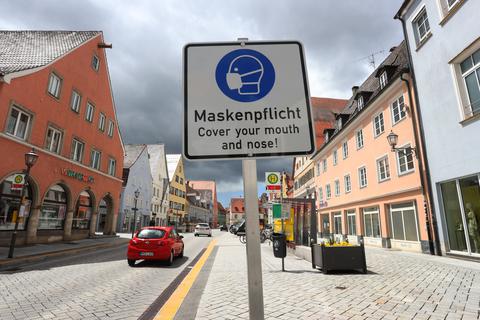 Auf einem Schild in einer Stadt wird auf Maskenpflicht hingewiesen. Foto: dpa/Karl-Josef Hildenbrand