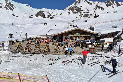 Skifahrer sitzen im österreichischen Obertauern während einer Pause auf der Terrasse einer geschlossenen Skihütte. Foto: dpa