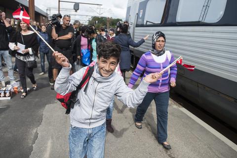 Dieser syrische Junge freut sich über die Ankunft in Dänemark und winkt mit Fähnchen. Nach ihm wurde der Bahnhof in Rødby für weitere Züge aus Deutschland zwischenzeitlich dicht gemacht. Foto: dpa