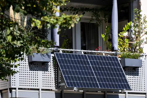 Eine kleine Solaranlage ist an einem Balkon eines Mehrparteienhauses angebracht. 