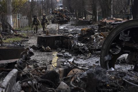 Zwei ukrainische Soldaten gehen auf einer Straße, die übersät ist mit zerstörten russischen Militärfahrzeugen. In der ukrainischen Stadt Butscha, 25 Kilometer nordwestlich der Hauptstadt Kiew, bietet sich nach dem Rückzug der russischen Armee ein Bild des Grauens.