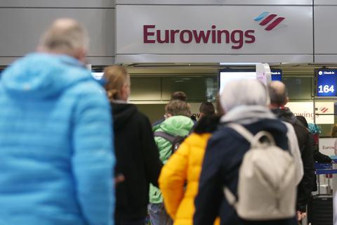 Passagiere stehen am Flughafen in einer Schlange, um für einen Eurowings-Flug nach Palma de Mallorca einzuchecken. Foto: dpa/David Young