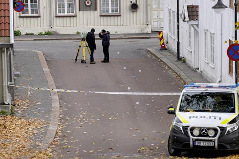 Zwei Polizisten ermitteln in der Nähe des Tatorts in der norwegischen Kleinstadt Kongsberg. Fünf Menschen starben.  Foto: dpa