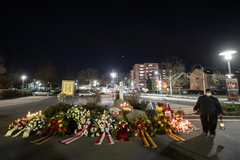 Ein Mann mit einem Grablicht in der Hand steht neben Blumengestecken, die an die Opfer erinnert. Ein Rechtsextremist hatte in Hanau am 19. Februar 2020 neun Menschen aus rassistischen Motiven erschossen. Foto: dpa Foto: dpa