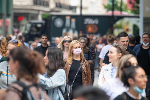 Eine Frau trägt in einer Gruppe von Fußgängern einen Mund-Nasen-Schutz. Foto: dpa