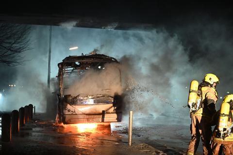 Feuerwehrmänner löschen an der Berliner Sonnenallee einen Reisebus, der von Unbekannten angezündet worden ist.