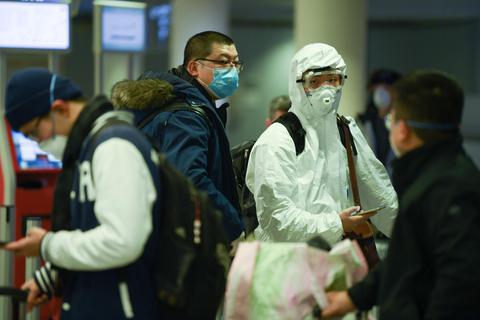 Beklemmendes Bild: Passagiere mit Mundschutz und Atemmaske warten vor den Check-in-Schaltern von Air China. Foto: dpa
