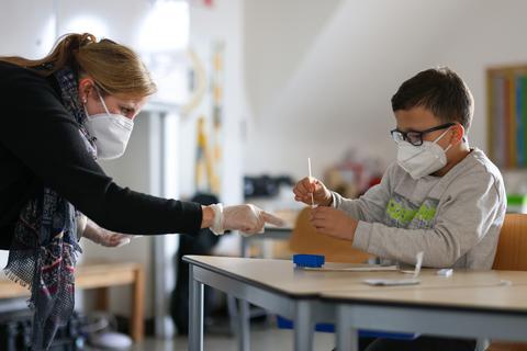 Schulkinder in Wiesbaden testen sich mit Unterstützung einer Lehrerin im Klassenraum. Foto: Jörg Halisch