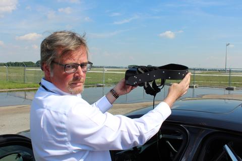 Martin Schulze Beerhorst zeigt die VR-Brille. Die silbernen Punkte dienen dem Headtracker auf dem Rücksitz dazu, die Kopf- und damit die Augenbewegungen des Fahrers in die virtuelle Szenerie zu übertragen. Foto: Chowanetz